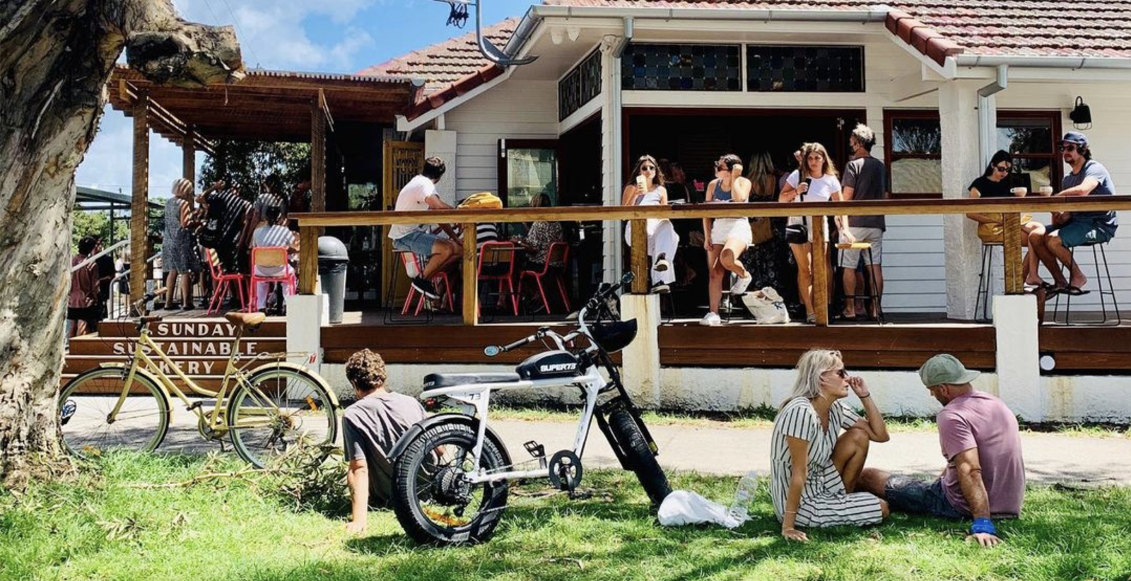 Exterior shot of Byron Bay Cafe 'sunday sustainable bakery' with people sitting in the sun