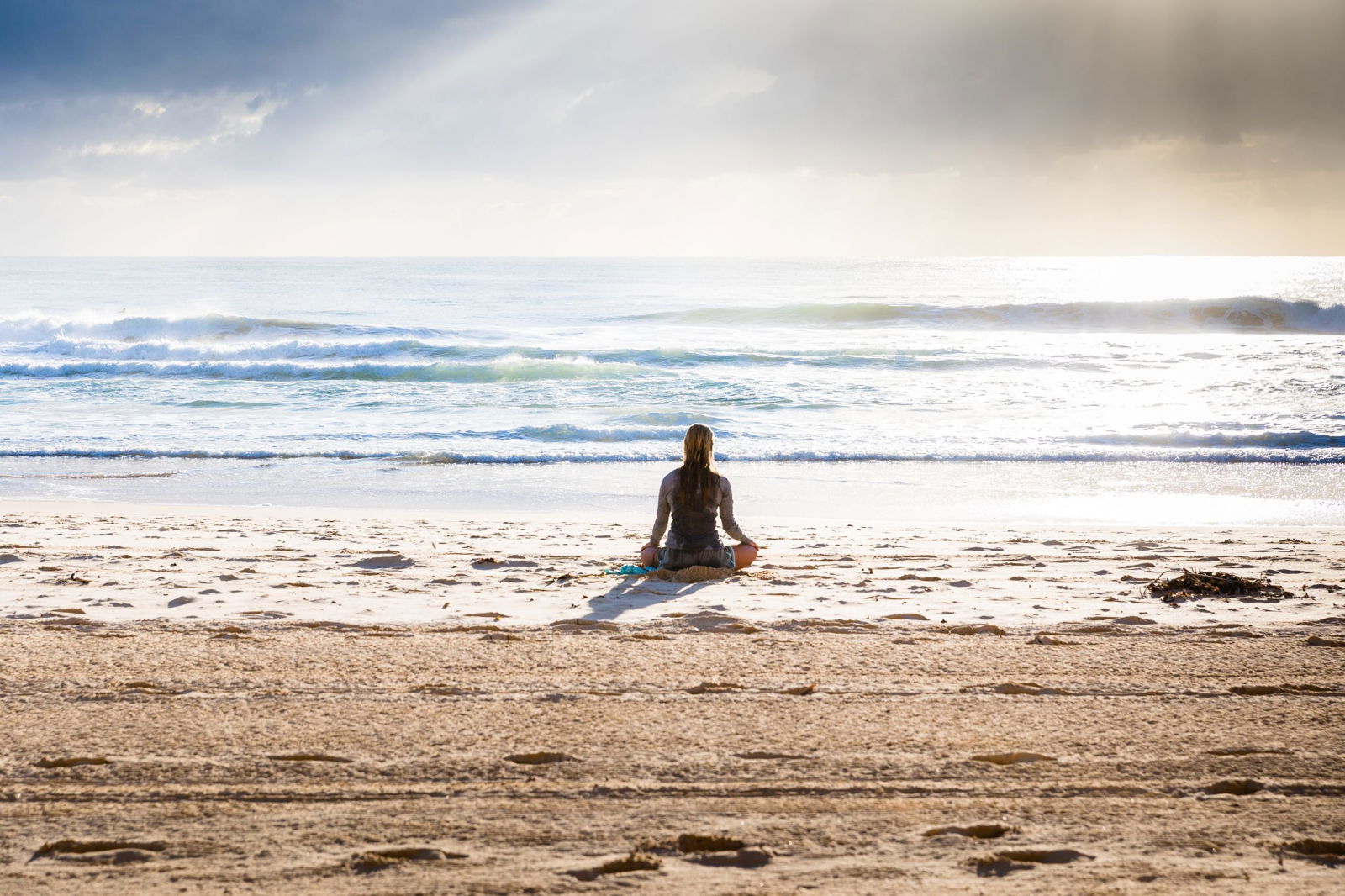 Woman sitting in front of the beach outside of Sattva Yoga in Byron Bay